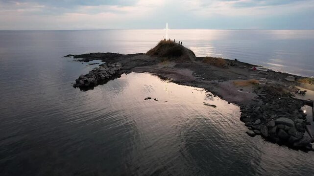 Aerial view of a radiant white cross standing tall atop a rocky land formation surrounded by the tranquil sea, Lozenets, Tsarevo, Bulgaria.