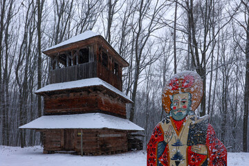 Winter landscape with historic wooden bell tower and folk art figure Shevchenko Grove. Lviv. Ukraine