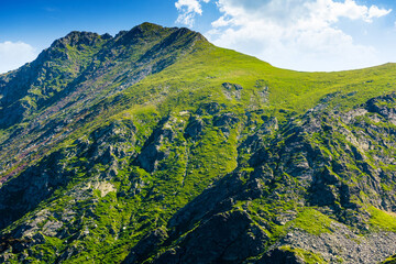 romania mountain landscape in summer. fagaras ridge on a sunny day under blue sky with clouds. alpine scenery with rocky peaks and steep slopes. horizontal travel background of scenic place for hiking