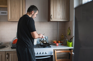 A bearded man prepares breakfast, fries an omelette