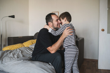 Father and son wrestle and play in bed in the morning after waking up. Morning hugs with a child