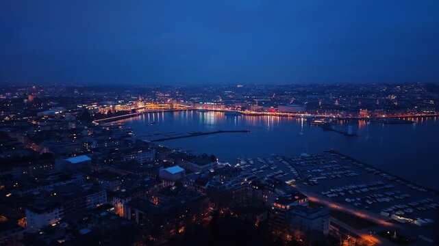 Aerial view of the Geneva cityscape, with lights reflecting off the water, creating a stunning contrast with the dark sky, Rade of Geneva, Geneva, Switzerland.