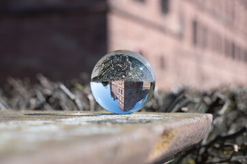 A glass sphere reflecting a castle; the sphere rests on a wall.