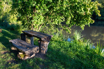 Picnic table and bench by a lake in green nature