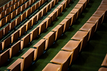 Background image of empty stands with multiple rows and empty seats. Orange fan seats are empty. News about fans and watching sports from stands. Cheering on your favorite sports team at stadium