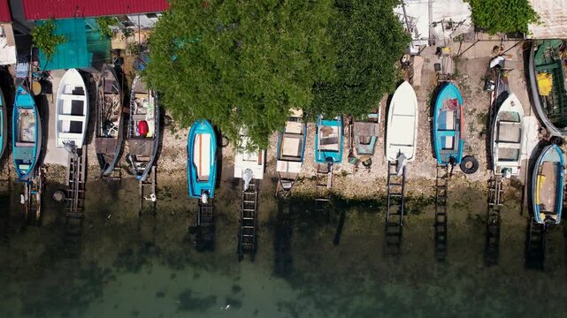 Aerial view of vibrant fishing boats resting on the shore, creating a mosaic of colors against the clear water, Balchik, Dobrich Province, Bulgaria.