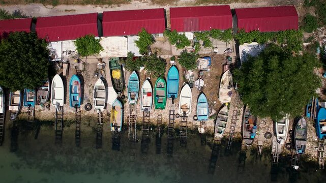 Aerial view of colorful boats lined along the shore with red roofs and green foliage creating a vibrant contrast, Balchik, Dobrich Province, Bulgaria.