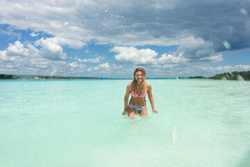 Young woman enjoying clear turquoise water splashing in bacalar,mexico
