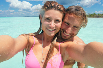 Happy couple enjoying summer vacation selfie in turquoise water in bacalar,mexico
