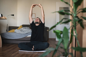 A bearded man wakes up in bed in a good mood, stretches, exercises, does morning exercises, and does yoga poses. Meditation and time for himself