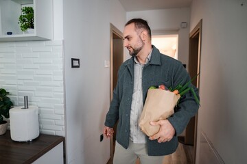 Man returning home with grocery shopping bag