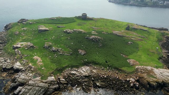 Aerial view of lush Dalkey Island featuring the historic Martello Tower, its green fields contrasting against the rugged, rocky coastline, Dalkey Island, County Dublin, Ireland.