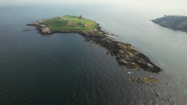 Aerial view of Dalkey Island, a green and rocky island surrounded by the dark blue sea, contrasting with the distant land, Dalkey Island, County Dublin, Ireland.