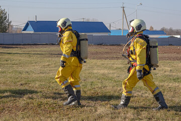 A group of rescuers equipped with breathing apparatus at the scene of an accident at a petrochemical plant. Elimination of an accident at a petrochemical plant. There is an emergency at the factory.