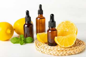 Lemon essential oil in a bottle with sliced ​​lemon and leaves on a wooden background. Lemon oil. Perfume bottle with aromatic essential oil. Serum, lemon extract. Vitamin C. Natural cosmetics. 