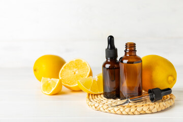 Lemon essential oil in a bottle with sliced ​​lemon and leaves on a wooden background. Lemon oil. Perfume bottle with aromatic essential oil. Serum, lemon extract. Vitamin C. Natural cosmetics. 