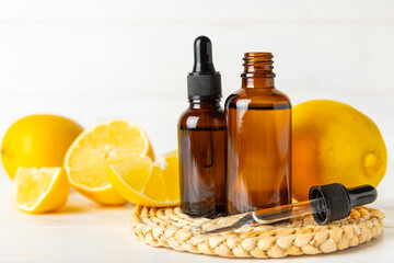 Lemon essential oil in a bottle with sliced ​​lemon and leaves on a wooden background. Lemon oil. Perfume bottle with aromatic essential oil. Serum, lemon extract. Vitamin C. Natural cosmetics. 