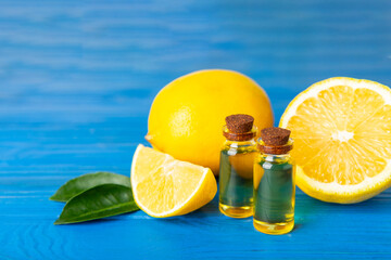Lemon essential oil in a bottle with sliced ​​lemon and leaves on a wooden background. Lemon oil. Perfume bottle with aromatic essential oil. Serum, lemon extract. Vitamin C. Natural cosmetics. 