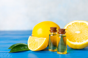 Lemon essential oil in a bottle with sliced ​​lemon and leaves on a wooden background. Lemon oil. Perfume bottle with aromatic essential oil. Serum, lemon extract. Vitamin C. Natural cosmetics. 