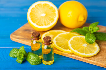 Lemon essential oil in a bottle with sliced ​​lemon and leaves on a wooden background. Lemon oil. Perfume bottle with aromatic essential oil. Serum, lemon extract. Vitamin C. Natural cosmetics. 