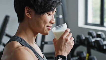 Strong athlete savoring a protein shake in a contemporary gym, showcasing muscular arms and a focused demeanor. Scene captures post-workout satisfaction and dedication to fitness.