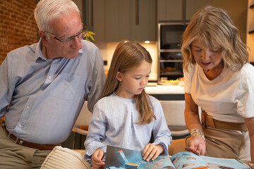 Grandparents and granddaughter bonding while reading an illustrated book together