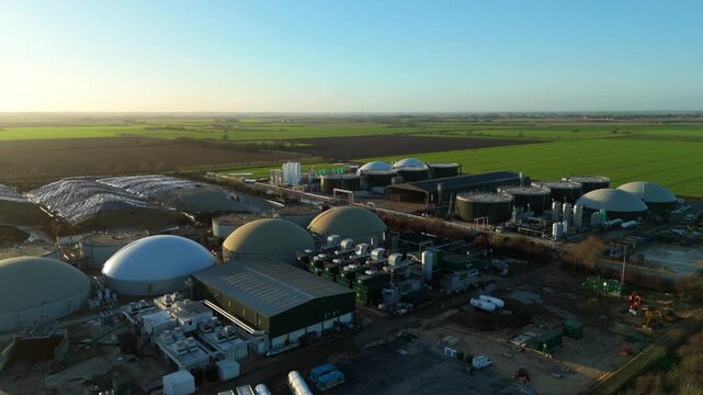 Aerial view of a sprawling biogas plant featuring dome-shaped structures against a backdrop of green fields, Chatteris, England, United Kingdom.