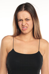 Fototapeta premium Studio shot of a natural woman with long dark hair wearing a black top, disgusted expression, portrait on a white background
