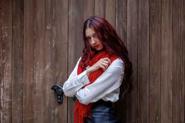 Young woman posing in front of wooden door with red scarf