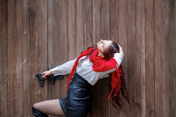 Young woman posing in front of wooden door with red scarf