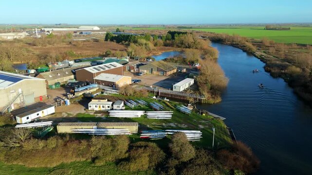 Aerial view of River Great Ouse and the adjacent land with boats, buildings, and lush greenery that showcases contrasting colors and textures, ELY, England, United Kingdom.