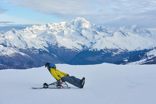 Man resting on sit ski enjoying alpine mountain view in winter