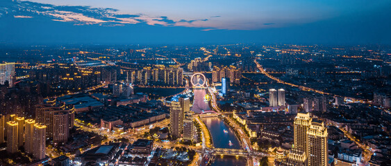 Fototapeta premium Aerial view of the Haihe River and Tianjin Eye Ferris wheel at night in Tianjin, China.
