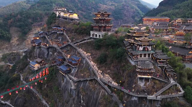 Aerial view of Wangxian Valley's cliffside buildings and walkways, presenting a contrast of traditional architecture against the rugged terrain, Wangxian Valley, China.