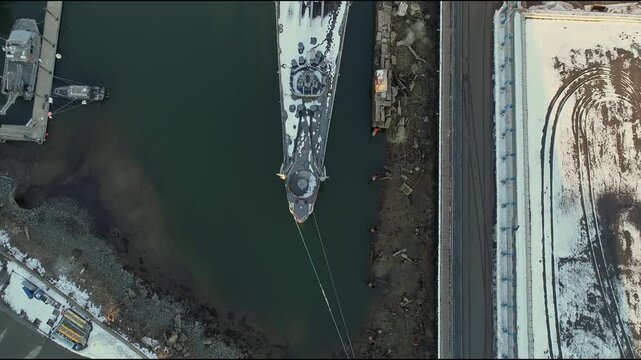 Aerial view of the USS Salem docked next to many storage tanks, contrasting dark water with the snow dusted structures, Boston, Massachusetts, United States.