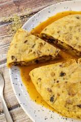 Spanish tortilla slices on white plate with sauce