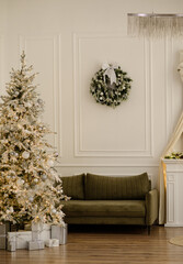 A bright room with a green sofa and a decorated white Christmas tree with yellow lights