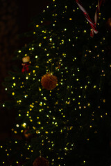 A decorated New Year's tree with lights shining in the evening in a dark room