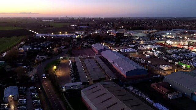Aerial view of the industrial area with warehouses and parked vehicles contrasting with the twilight sky, Peterborough, England, United Kingdom.