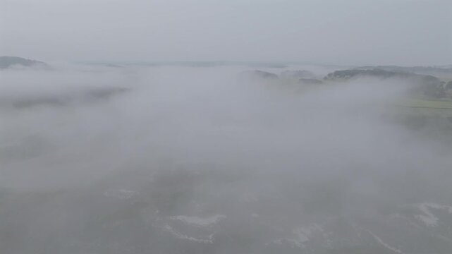 Aerial view of a landscape shrouded in a thick blanket of dense fog, obscuring details and creating an ethereal, mysterious atmosphere, Gloucester, Massachusetts, United States.