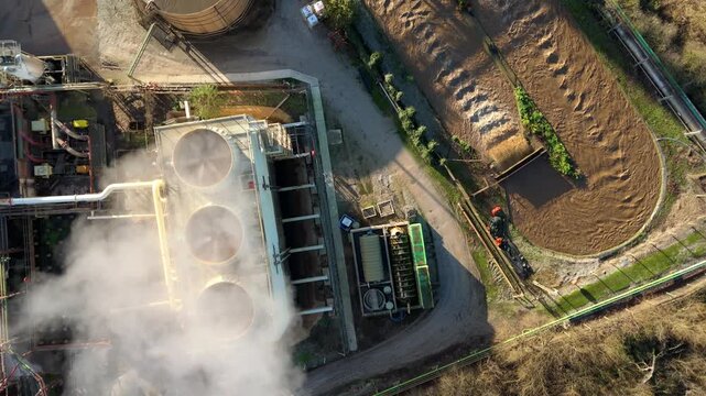 Aerial view of industrial buildings with cooling towers expelling steam and water treatment plant, seen from above, King's Lynn, England, United Kingdom.