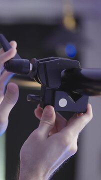 Person mounting clamps on pole between walls on video production set close-up