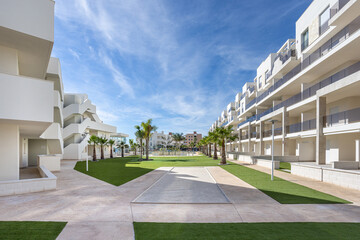 Contemporary apartment buildings with palm trees and landscaped garden under blue sky