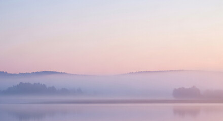 A beautiful sunrise reflects orange light over the misty river landscape as fog settles under a glowing sky at dawn