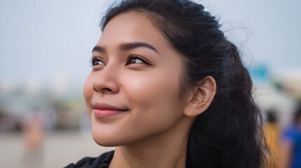 Young woman with a gentle smile looks thoughtfully upwards in a serene outdoor portrait with soft lighting