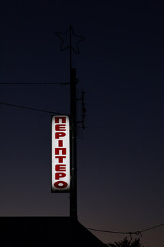 Illuminated Kiosk Sign on Urban Street at Night in Greece
