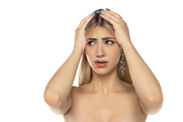 Fototapeta premium Studio shot of a worried woman touching her head with both hands, looking anxious and stressed, on a white background