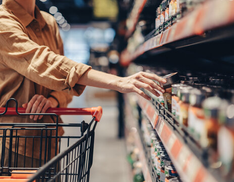 Kobieta robiąca zakupy w markecie i zdejmująca produkty z p&oacute;łki