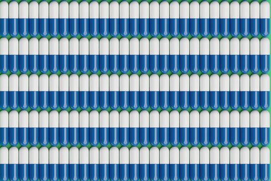 White and blue pills on green surface. Top flat view