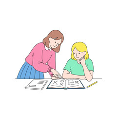 Two girls studying together and discussing a book at a table  